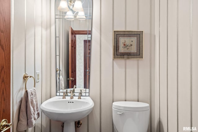 bathroom featuring toilet, a notable chandelier, and sink