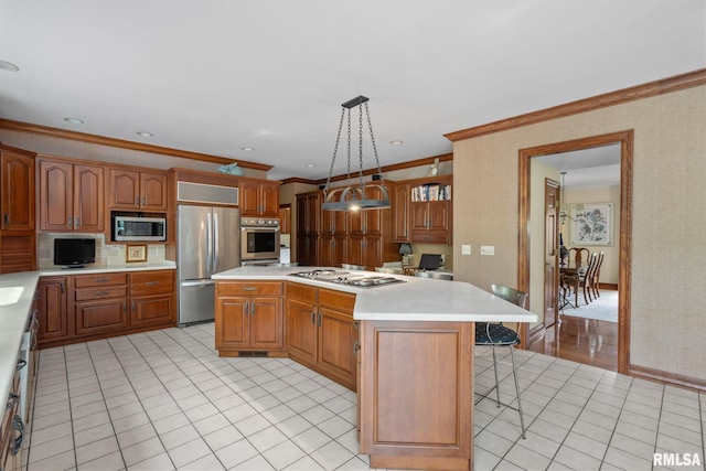 kitchen with decorative light fixtures, a kitchen island, ornamental molding, and stainless steel appliances