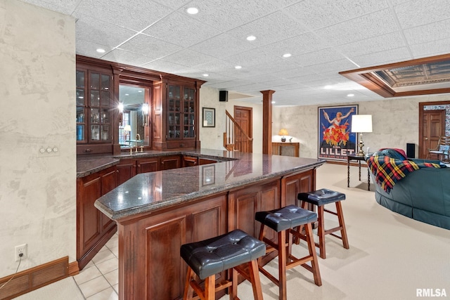 bar with dark stone countertops, ornate columns, and sink