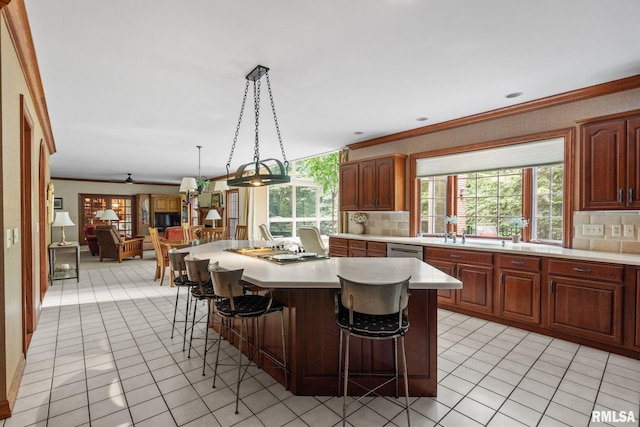 kitchen with a breakfast bar area, backsplash, a kitchen island with sink, and decorative light fixtures