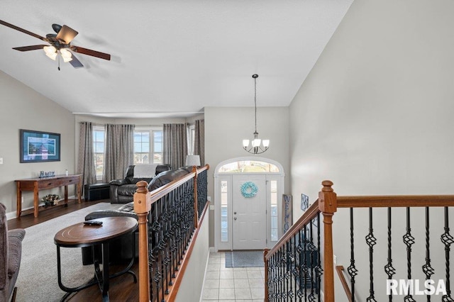 foyer entrance featuring light tile patterned floors, ceiling fan with notable chandelier, and high vaulted ceiling