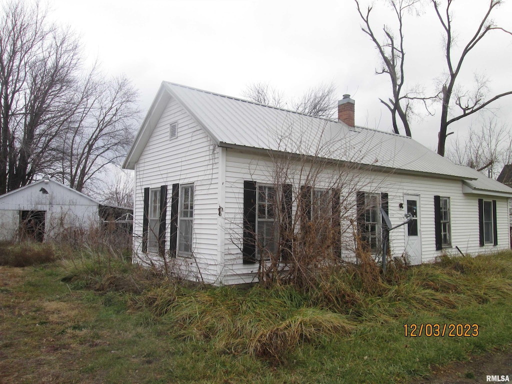 view of side of property with a chimney and metal roof