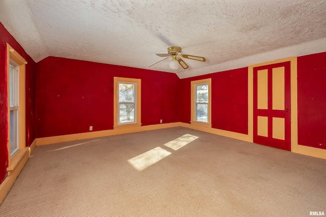 empty room featuring carpet, a textured ceiling, ceiling fan, and lofted ceiling