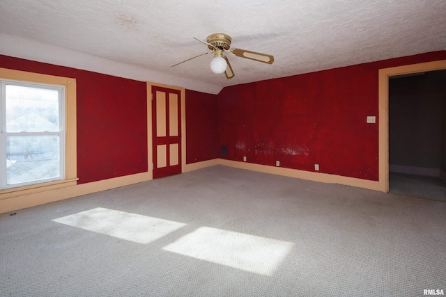 empty room with carpet flooring, ceiling fan, and a textured ceiling