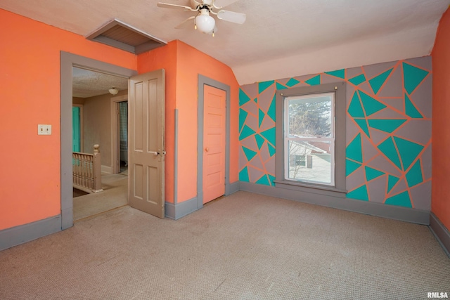 unfurnished bedroom with ceiling fan, a closet, carpet, and vaulted ceiling