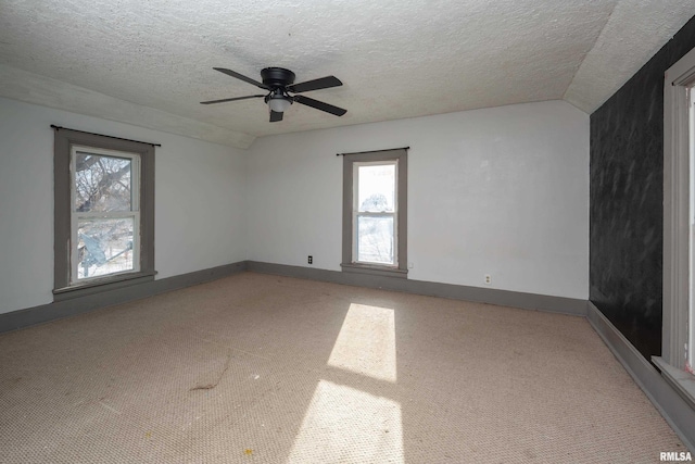 carpeted spare room featuring ceiling fan, lofted ceiling, and a textured ceiling