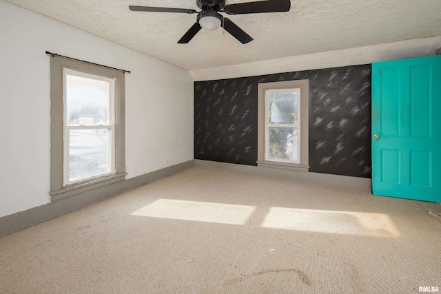 empty room with ceiling fan, a textured ceiling, and a wealth of natural light