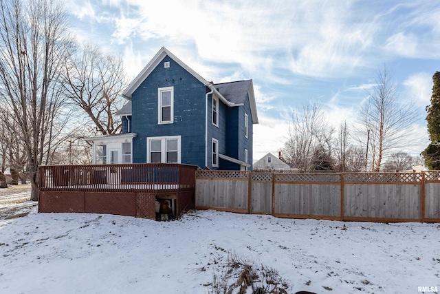 snow covered house with a wooden deck