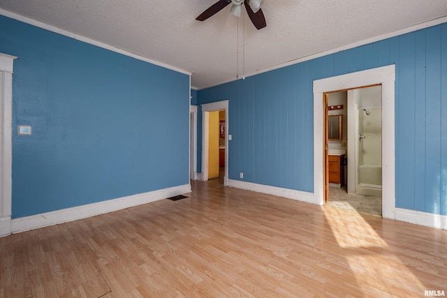 empty room featuring a textured ceiling, light hardwood / wood-style floors, ceiling fan, and crown molding