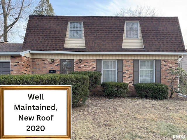 view of front of house with mansard roof, brick siding, and roof with shingles