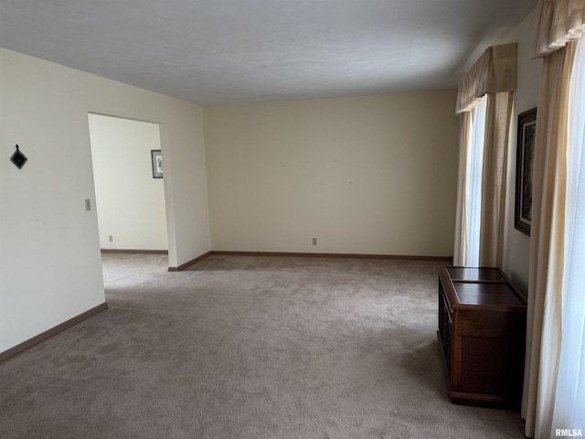 empty room featuring baseboards and light carpet