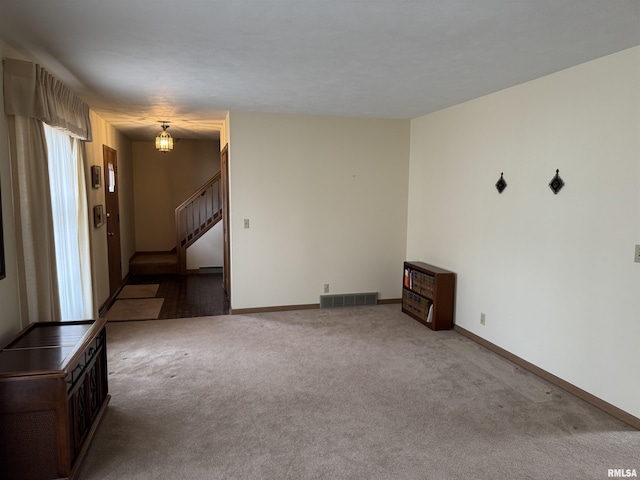 unfurnished living room featuring stairs, carpet flooring, baseboards, and visible vents