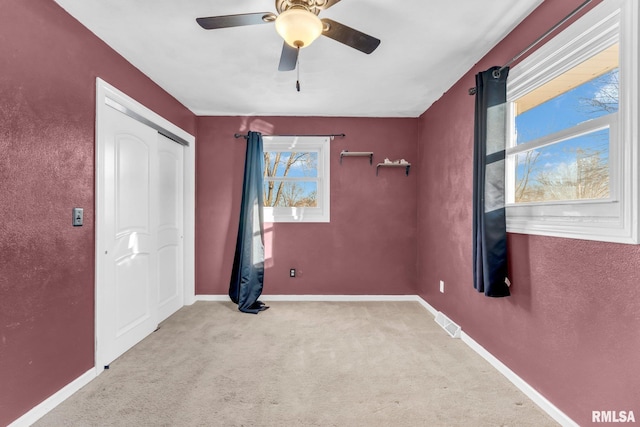 carpeted empty room with ceiling fan and a healthy amount of sunlight