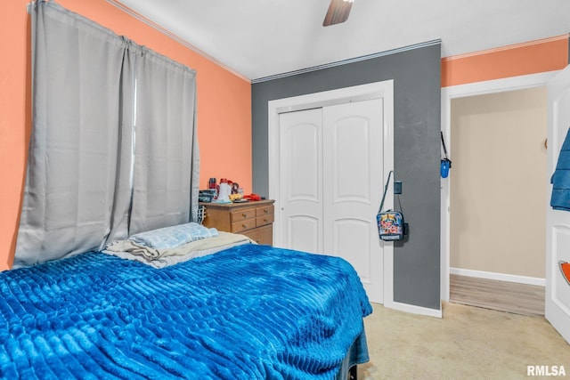 carpeted bedroom with a closet, ceiling fan, and crown molding