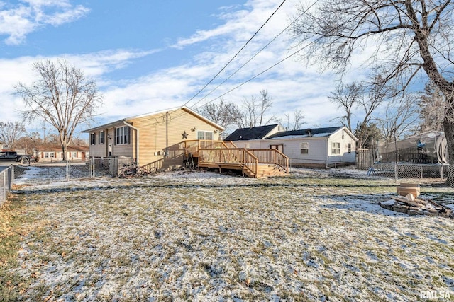 rear view of house with a trampoline, a deck, and a fire pit