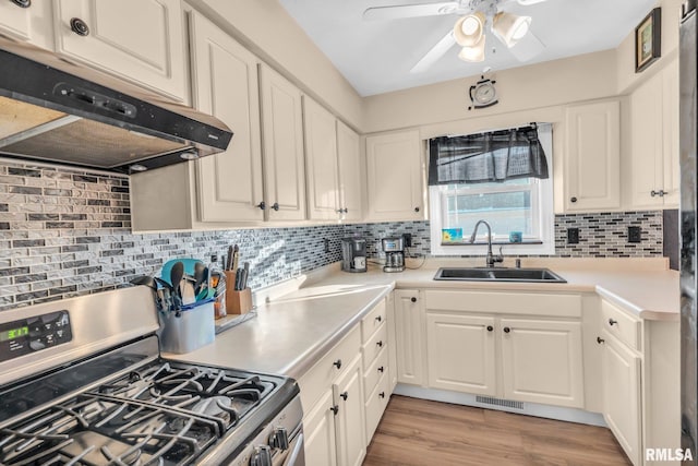 kitchen featuring stainless steel gas range, white cabinetry, ceiling fan, and sink