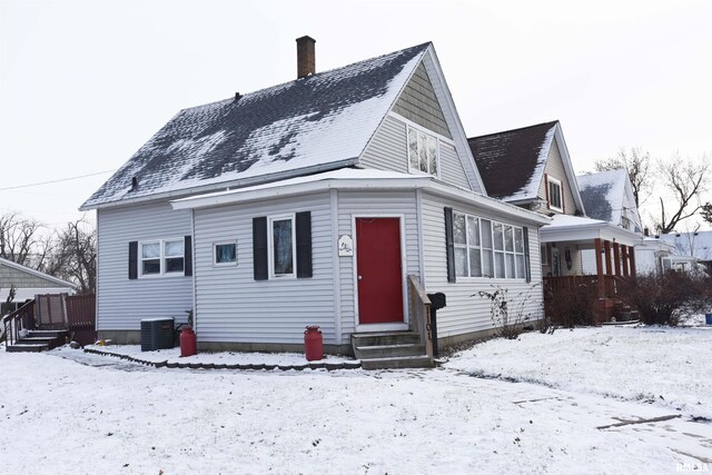 snow covered back of property featuring central air condition unit