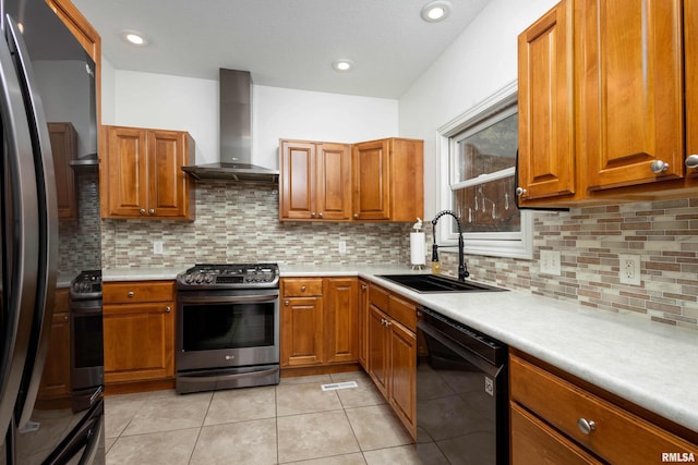 kitchen with appliances with stainless steel finishes, tasteful backsplash, wall chimney exhaust hood, sink, and light tile patterned floors