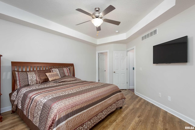 bedroom featuring a tray ceiling, ceiling fan, and wood-type flooring