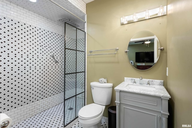 bathroom featuring tiled shower, ceiling fan, vanity, and toilet