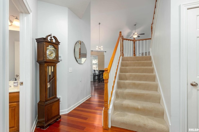 staircase with hardwood / wood-style floors and ceiling fan with notable chandelier