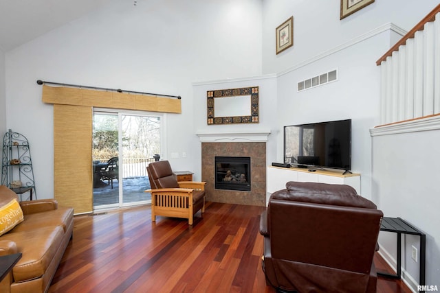 living room featuring dark hardwood / wood-style floors, a towering ceiling, and a tile fireplace