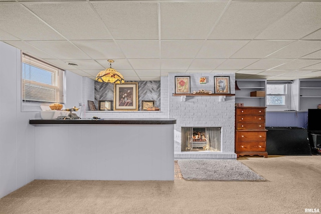 unfurnished living room with a paneled ceiling, carpet, and a brick fireplace