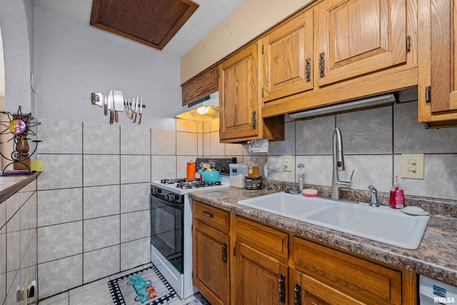 kitchen featuring white gas range, decorative backsplash, sink, and light tile patterned flooring