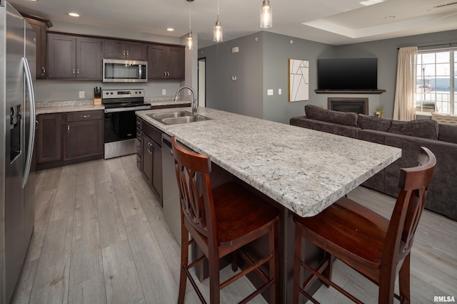 kitchen featuring a breakfast bar, dark brown cabinetry, stainless steel appliances, sink, and pendant lighting