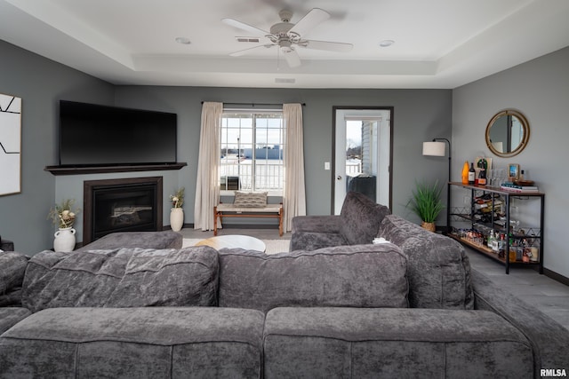 living room featuring wood-type flooring, a tray ceiling, and ceiling fan