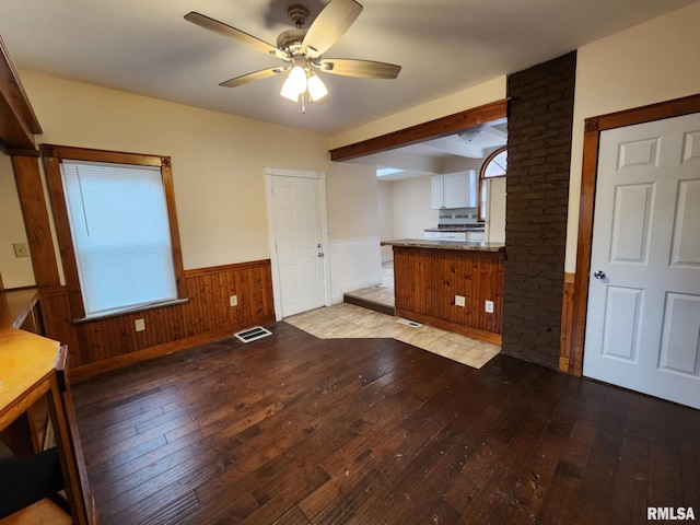 kitchen with kitchen peninsula, ceiling fan, light hardwood / wood-style flooring, and wood walls