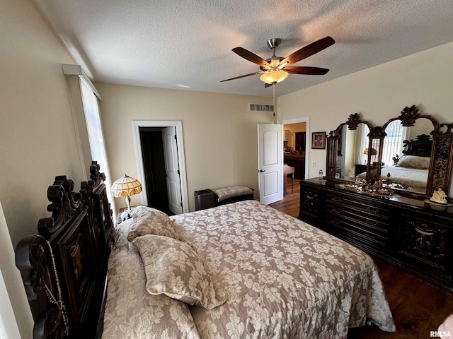 bedroom with ceiling fan, wood-type flooring, and a textured ceiling