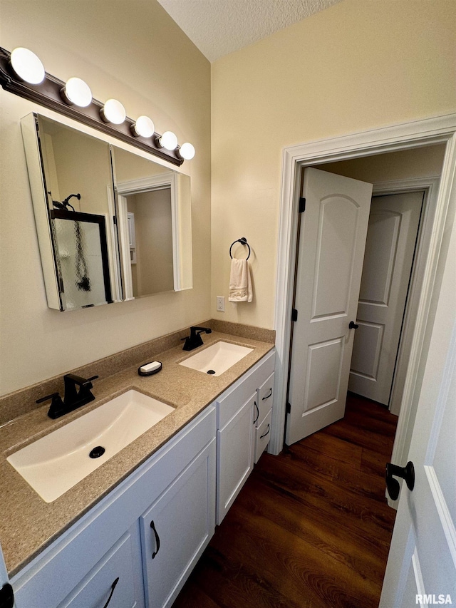 bathroom featuring vanity, an enclosed shower, a textured ceiling, and hardwood / wood-style flooring