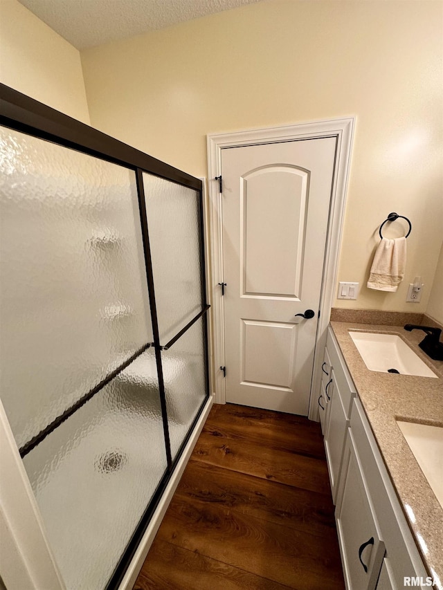 bathroom with vanity, hardwood / wood-style floors, a textured ceiling, and a shower with shower door