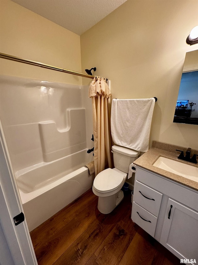 full bathroom featuring shower / bath combination with curtain, vanity, a textured ceiling, hardwood / wood-style floors, and toilet