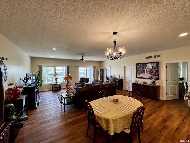 dining area with a textured ceiling, ceiling fan with notable chandelier, and dark wood-type flooring