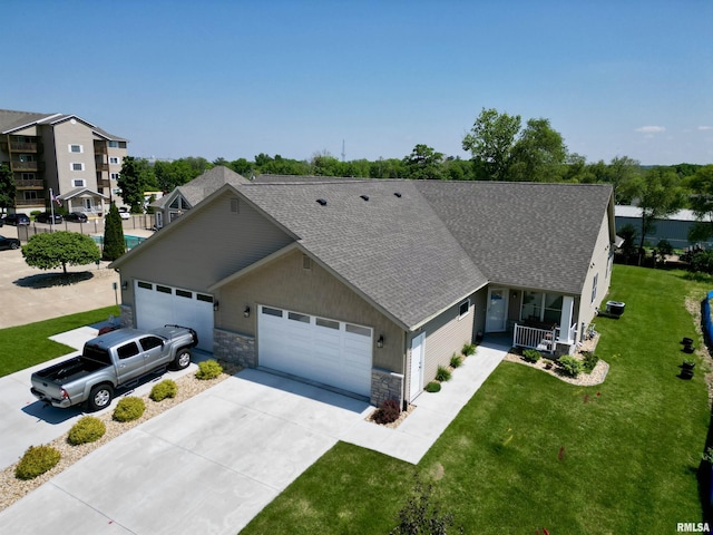 view of front of house with a garage, covered porch, a front yard, and central AC