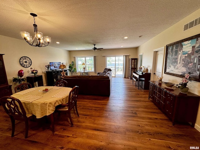 dining area with dark hardwood / wood-style flooring, ceiling fan with notable chandelier, and a textured ceiling