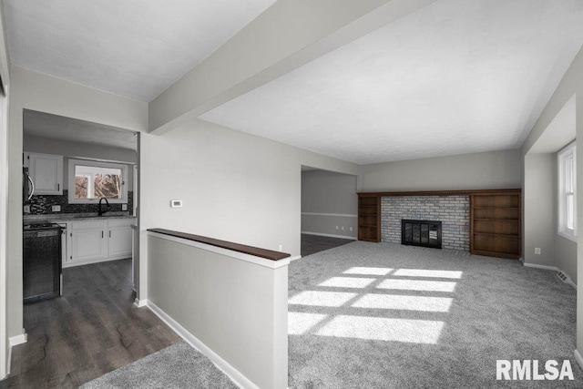 living room featuring dark hardwood / wood-style floors, beam ceiling, sink, and a fireplace