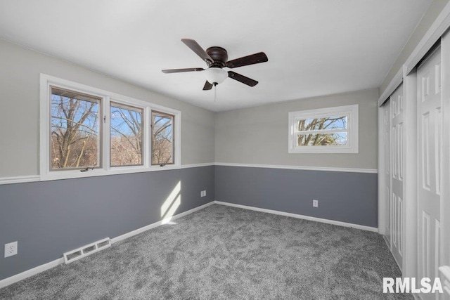 unfurnished bedroom featuring multiple windows, carpet, and ceiling fan