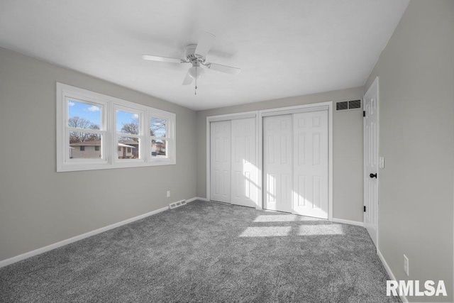 unfurnished bedroom featuring multiple closets, ceiling fan, and carpet