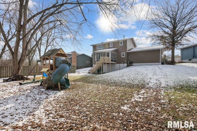 snow covered rear of property featuring a playground and a sunroom