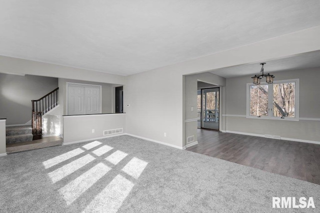 unfurnished living room with carpet flooring and an inviting chandelier