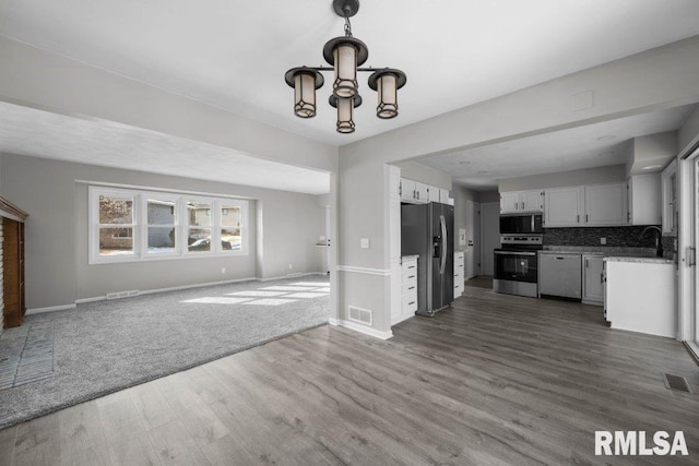 kitchen featuring an inviting chandelier, decorative backsplash, appliances with stainless steel finishes, dark hardwood / wood-style flooring, and white cabinetry