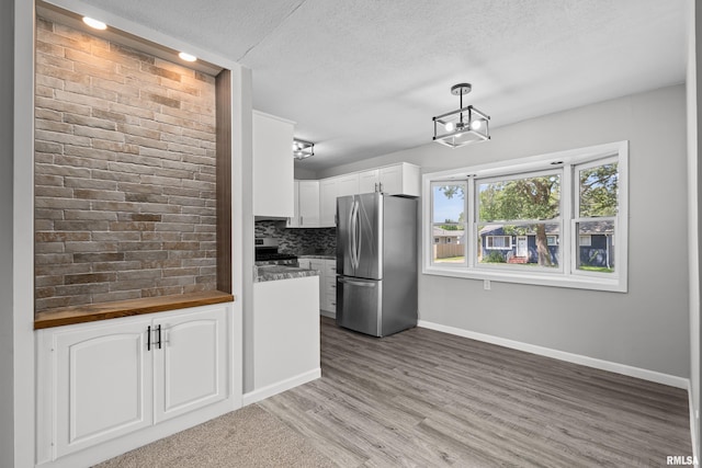 kitchen with appliances with stainless steel finishes, tasteful backsplash, decorative light fixtures, white cabinetry, and butcher block counters