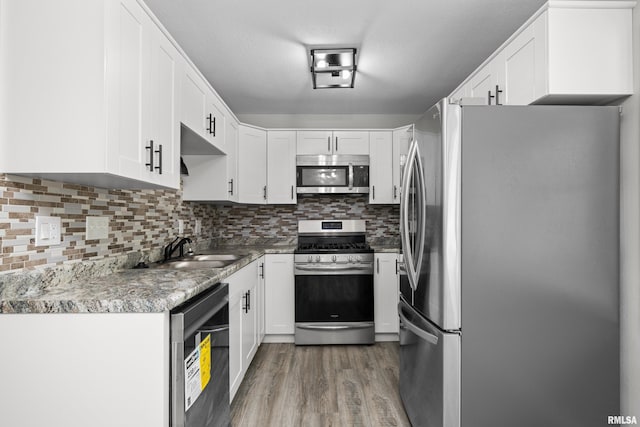 kitchen with decorative backsplash, white cabinetry, sink, and appliances with stainless steel finishes