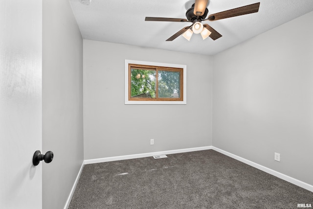 empty room featuring ceiling fan and dark carpet