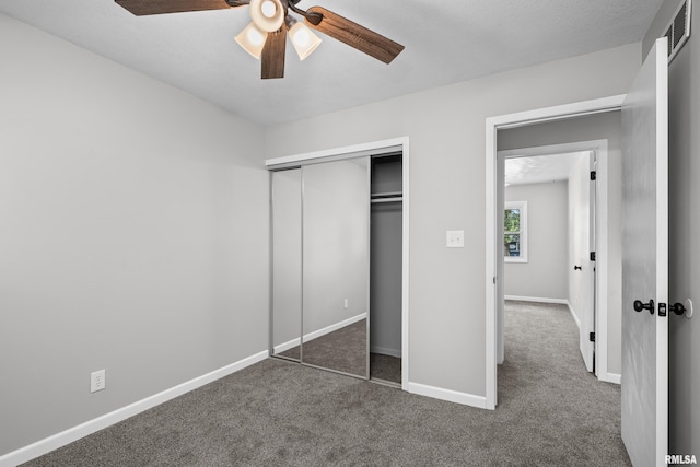 unfurnished bedroom with ceiling fan, a closet, and dark carpet