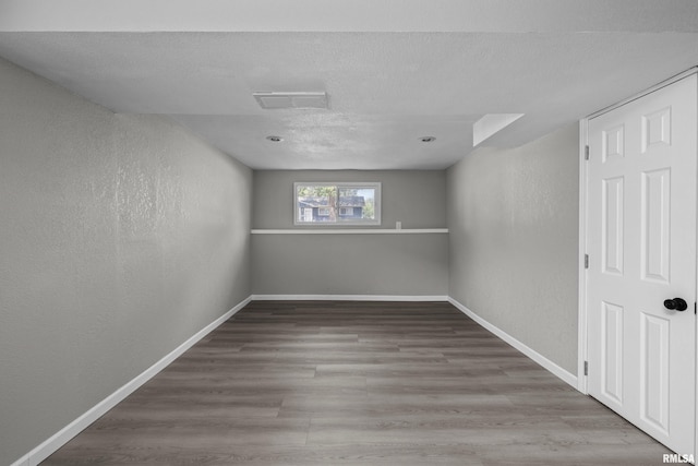 empty room with wood-type flooring and a textured ceiling