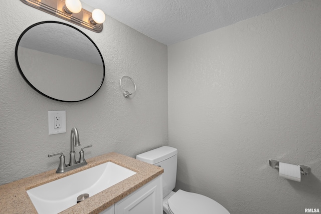 bathroom featuring vanity, a textured ceiling, and toilet